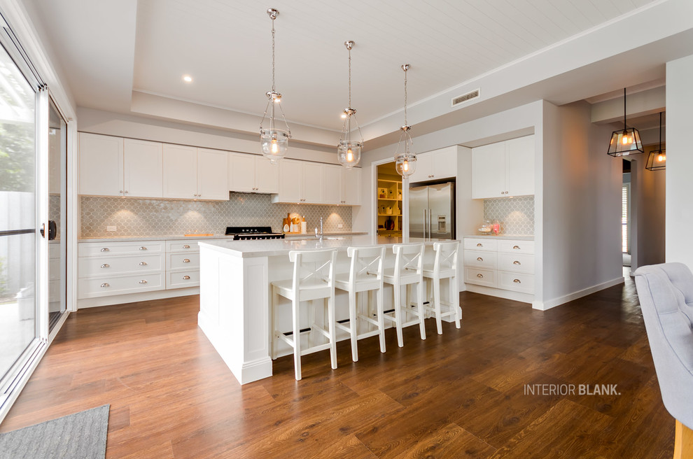 This is an example of a large beach style l-shaped kitchen pantry in Gold Coast - Tweed with an undermount sink, recessed-panel cabinets, white cabinets, quartz benchtops, blue splashback, porcelain splashback, black appliances, vinyl floors and with island.