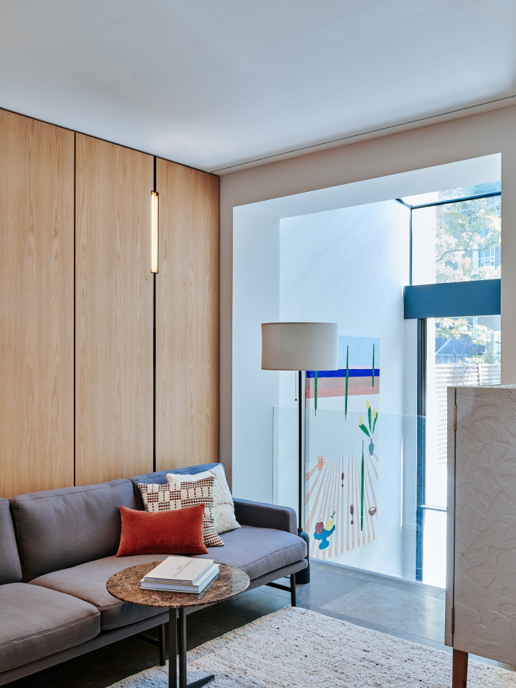 На фото: открытая гостиная комната среднего размера:: освещение в стиле ретро с белыми стенами, полом из известняка, серым полом и панелями на части стены с