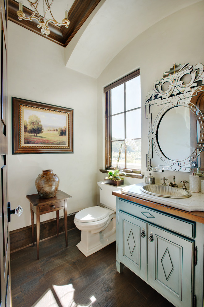 Design ideas for a small traditional powder room in Other with recessed-panel cabinets, turquoise cabinets, a two-piece toilet, beige tile, beige walls, dark hardwood floors, a drop-in sink, quartzite benchtops, brown floor and white benchtops.