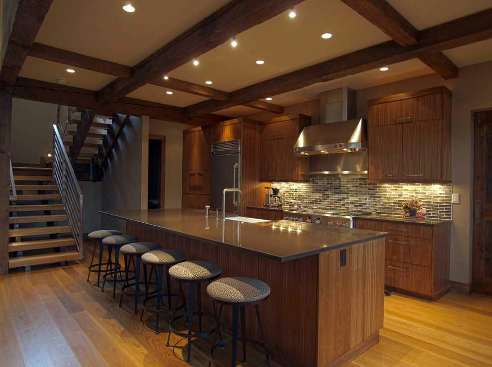 Eat-in kitchen - mid-sized rustic single-wall medium tone wood floor and beige floor eat-in kitchen idea in Phoenix with a farmhouse sink, flat-panel cabinets, dark wood cabinets, granite countertops, multicolored backsplash, stone tile backsplash, stainless steel appliances and an island