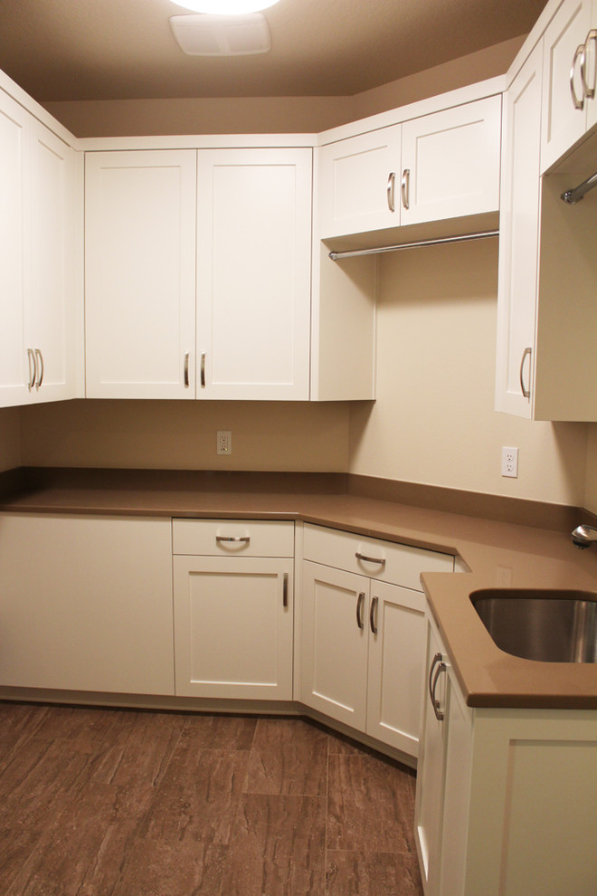 Photo of a mid-sized contemporary u-shaped dedicated laundry room in Portland with shaker cabinets, white cabinets, an undermount sink, a side-by-side washer and dryer, beige walls, ceramic floors, brown floor and brown benchtop.