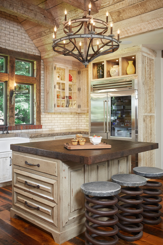 Inspiration for a country u-shaped kitchen in Grand Rapids with a farmhouse sink, distressed cabinets, beige splashback, subway tile splashback, dark hardwood floors and with island.