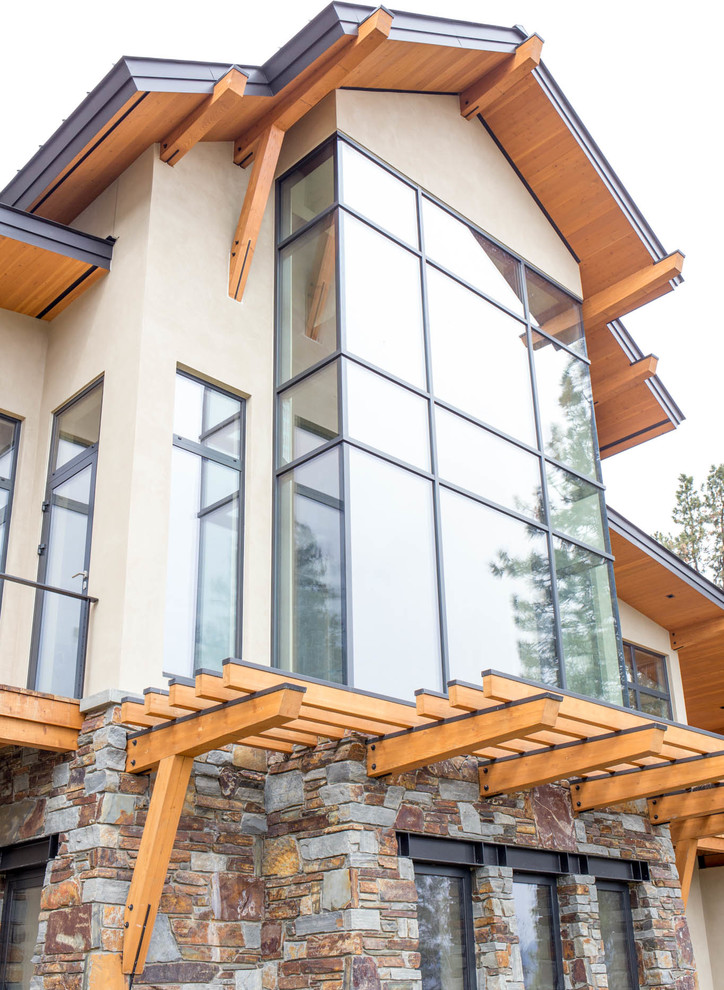Inspiration for a large rustic beige three-story stucco gable roof remodel