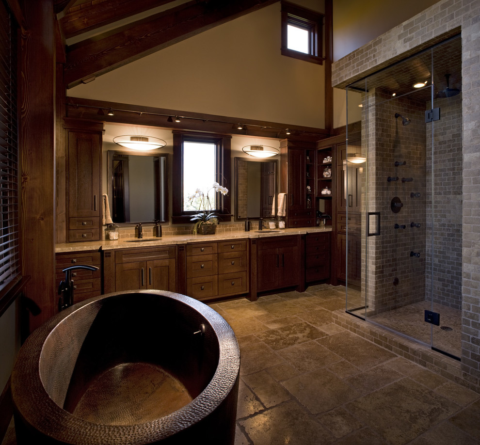 Inspiration for a large arts and crafts master bathroom in Calgary with shaker cabinets, dark wood cabinets, a freestanding tub, a curbless shower, beige walls, travertine floors and an undermount sink.