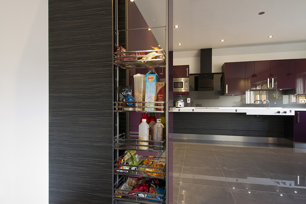Design ideas for a mid-sized contemporary l-shaped open plan kitchen in Essex with an integrated sink, flat-panel cabinets, purple cabinets, concrete benchtops, metallic splashback, glass sheet splashback, stainless steel appliances, porcelain floors and grey floor.