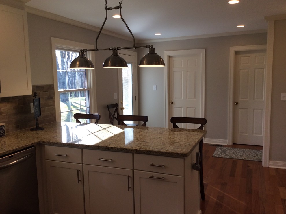 Inspiration for a transitional u-shaped medium tone wood floor kitchen remodel with an undermount sink, shaker cabinets, white cabinets, granite countertops, beige backsplash, subway tile backsplash, stainless steel appliances and a peninsula