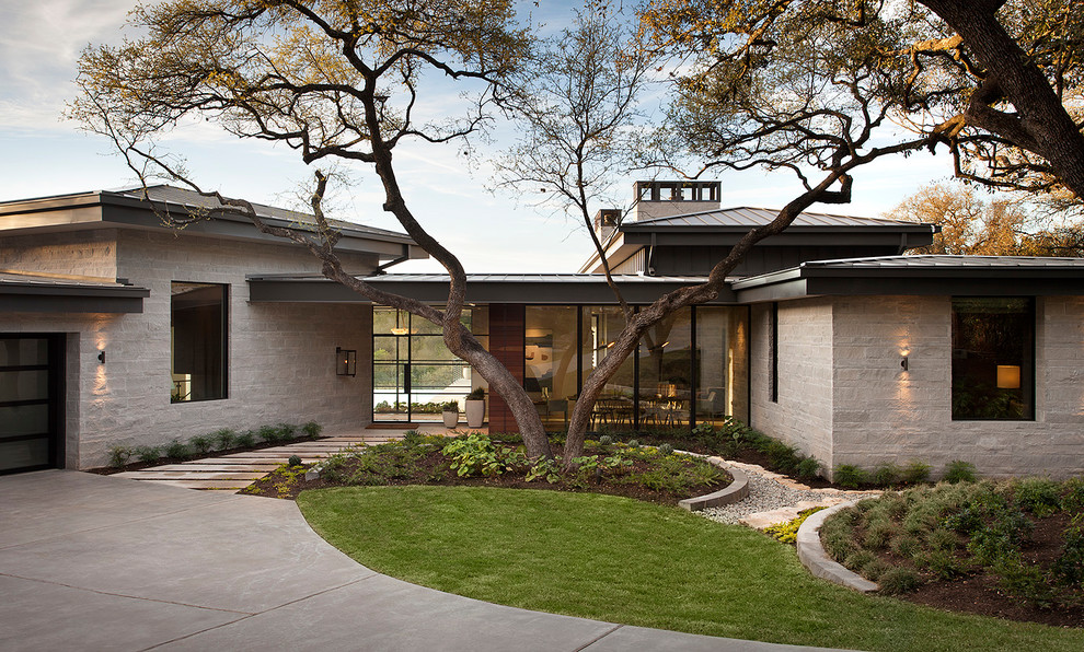 Contemporary one-storey grey house exterior in Austin with stone veneer and a hip roof.