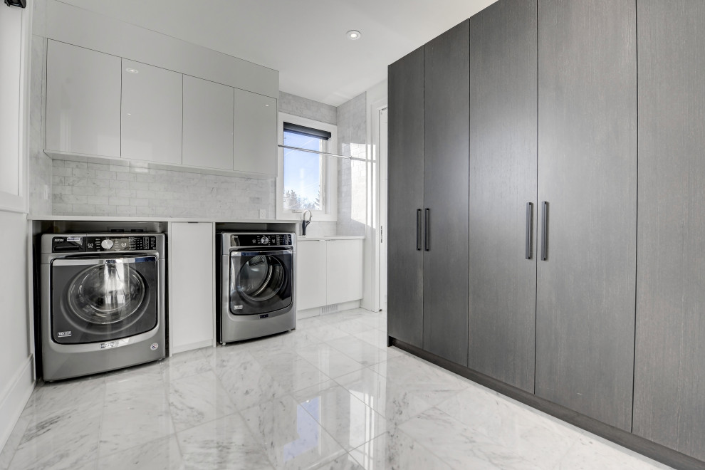 Inspiration for a large contemporary l-shaped dedicated laundry room in Calgary with an undermount sink, flat-panel cabinets, dark wood cabinets, quartz benchtops, grey splashback, ceramic splashback, white walls, ceramic floors, grey floor and white benchtop.