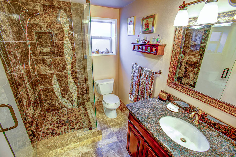 This is an example of a mid-sized tropical bathroom in Seattle with an undermount sink, raised-panel cabinets, dark wood cabinets, granite benchtops, a corner shower and brown tile.