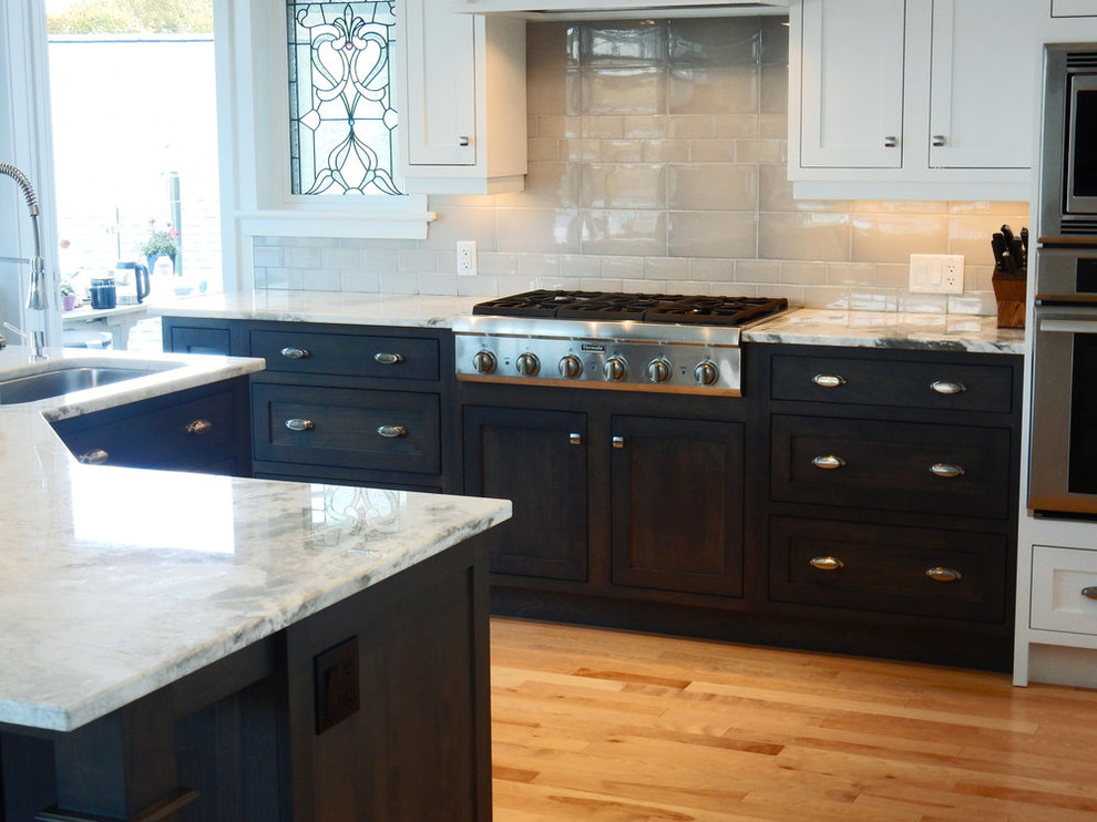 Inspiration for a mid-sized transitional l-shaped medium tone wood floor and brown floor open concept kitchen remodel with an undermount sink, beaded inset cabinets, white cabinets, quartz countertops, gray backsplash, ceramic backsplash, stainless steel appliances, an island and white countertops
