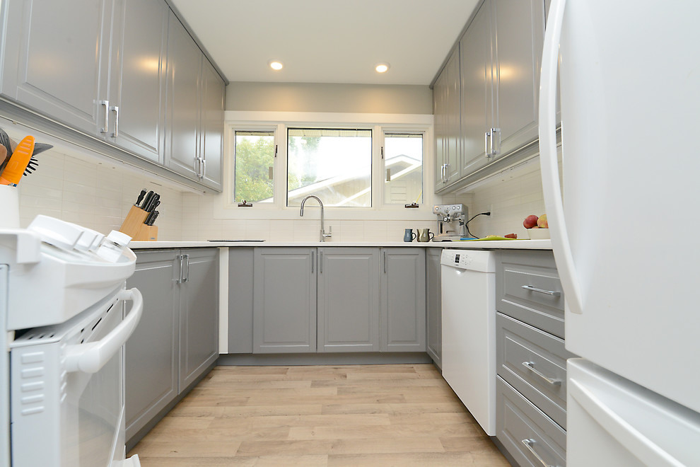 Small elegant u-shaped light wood floor and beige floor enclosed kitchen photo with an undermount sink, raised-panel cabinets, gray cabinets, quartz countertops, white backsplash, white appliances, no island and white countertops