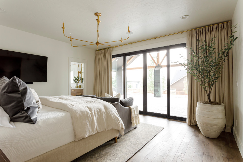 Modelo de dormitorio principal tradicional renovado de tamaño medio con paredes blancas y suelo de madera en tonos medios