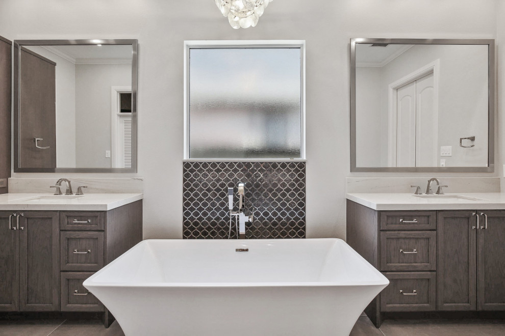 Inspiration for a medium sized contemporary ensuite bathroom in Houston with recessed-panel cabinets, grey cabinets, a freestanding bath, an alcove shower, grey tiles, ceramic tiles, grey walls, cement flooring, a submerged sink, engineered stone worktops, grey floors, a hinged door, white worktops, double sinks and a built in vanity unit.