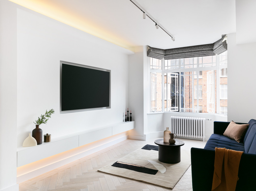 Medium sized contemporary open plan games room in London with white walls, light hardwood flooring, a built-in media unit and beige floors.