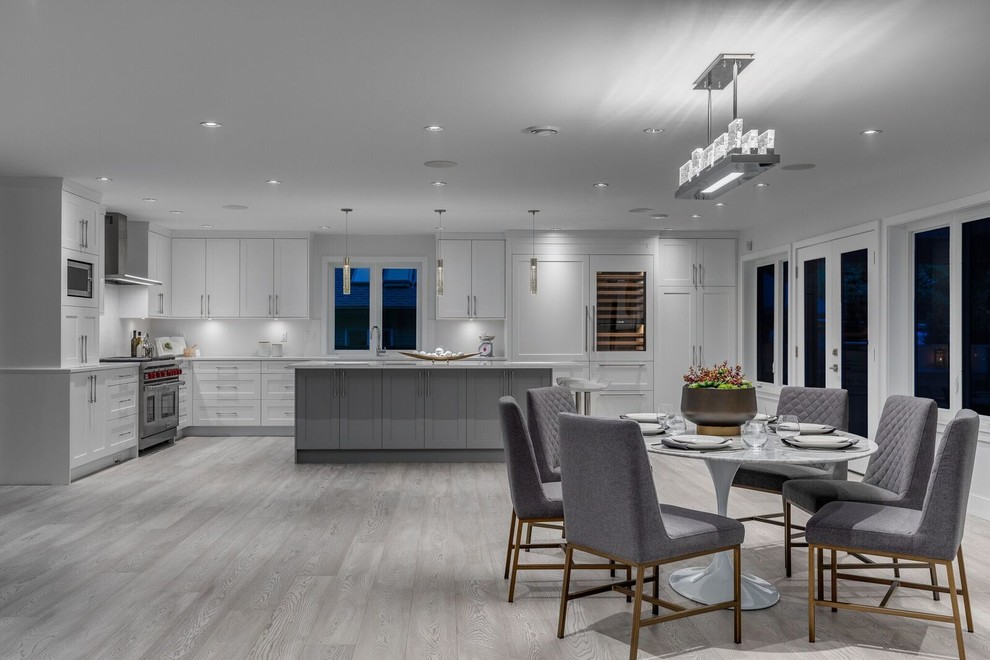 This is an example of a large modern open plan dining in Vancouver with white walls, light hardwood floors, beige floor, a standard fireplace and a tile fireplace surround.