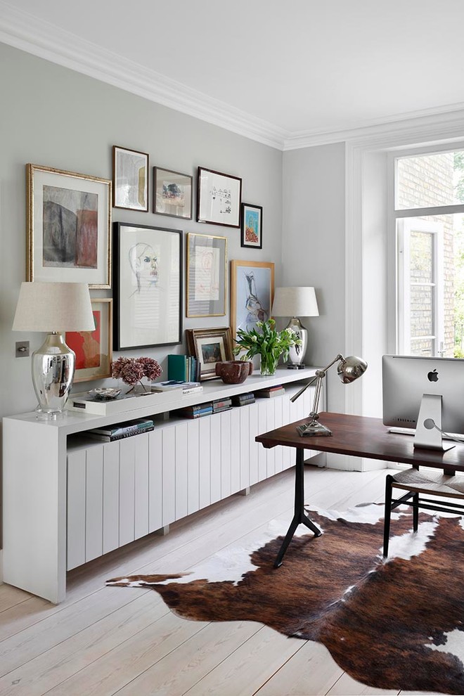 Inspiration for a transitional study room in London with grey walls, light hardwood floors and a freestanding desk.