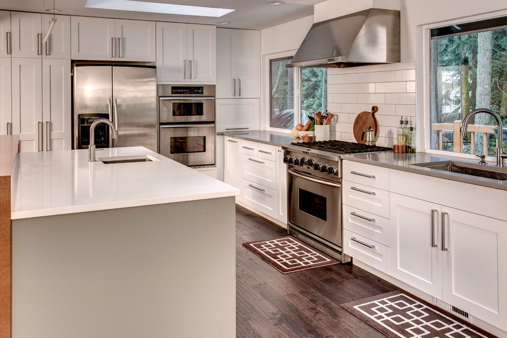 Open concept kitchen - transitional l-shaped medium tone wood floor open concept kitchen idea in Seattle with an undermount sink, shaker cabinets, white cabinets, quartz countertops, white backsplash, subway tile backsplash, stainless steel appliances and an island