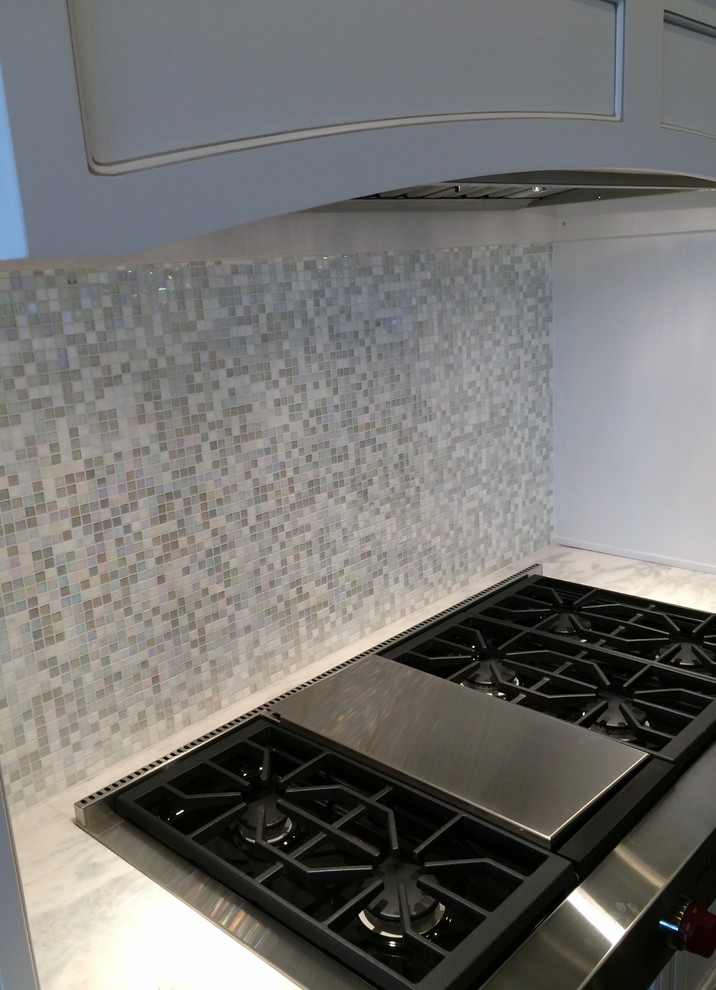 Inspiration for a large transitional galley dark wood floor home design remodel in Tampa with a farmhouse sink, recessed-panel cabinets, white cabinets, marble countertops, white backsplash, glass tile backsplash, paneled appliances and an island