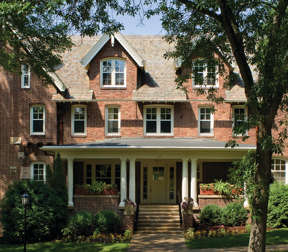 This is an example of an expansive traditional three-storey brick red house exterior in Other with a gable roof and a shingle roof.