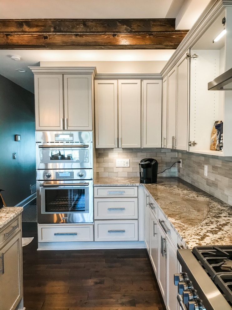 Example of a transitional kitchen design with flat-panel cabinets, gray cabinets, granite countertops, gray backsplash, porcelain backsplash and an island