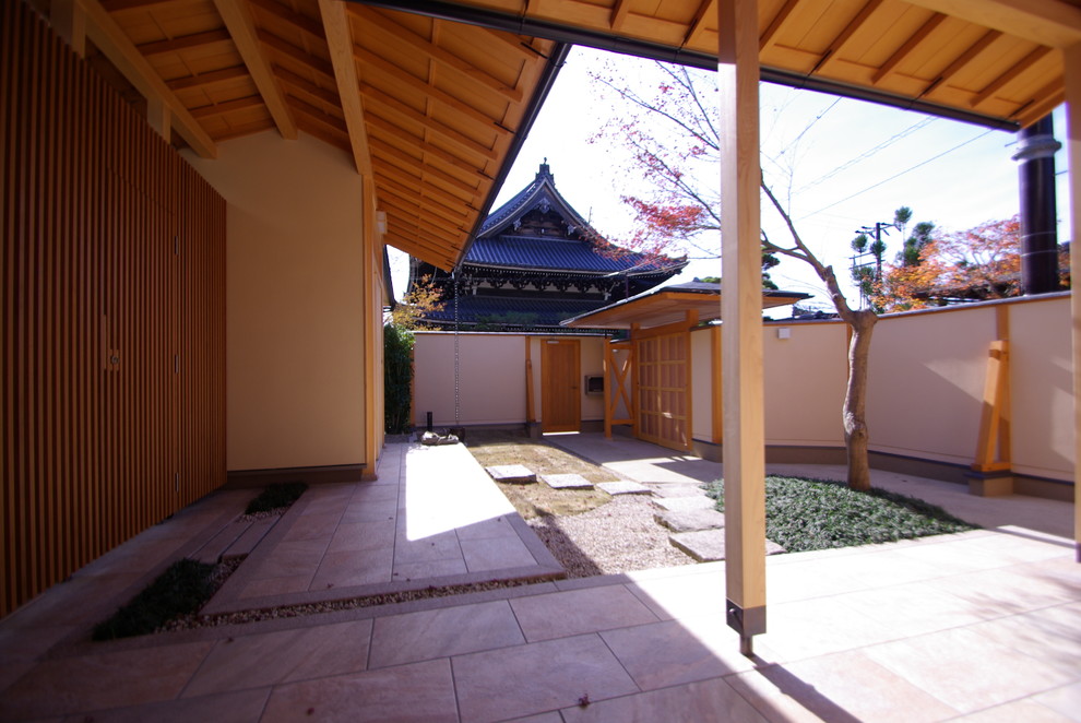 Asian front yard patio in Kyoto with natural stone pavers and a roof extension.