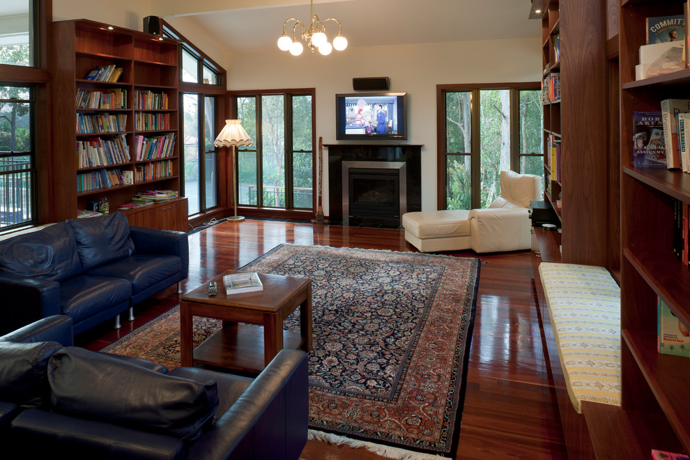 Large traditional enclosed family room in Brisbane with a library, white walls, dark hardwood floors, a standard fireplace, a tile fireplace surround and a wall-mounted tv.