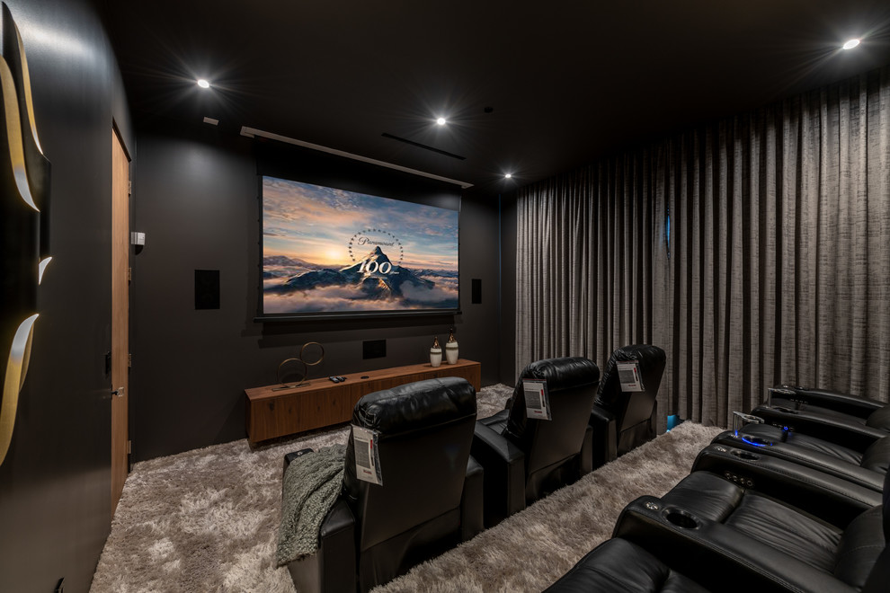 Contemporary enclosed home theatre in Los Angeles with black walls, carpet, a projector screen and grey floor.