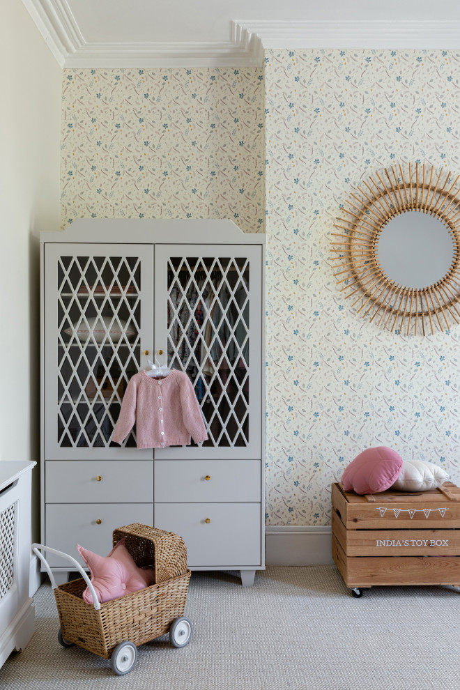 This is an example of a mid-sized traditional nursery for girls in London with beige walls, carpet, beige floor, coffered and wallpaper.