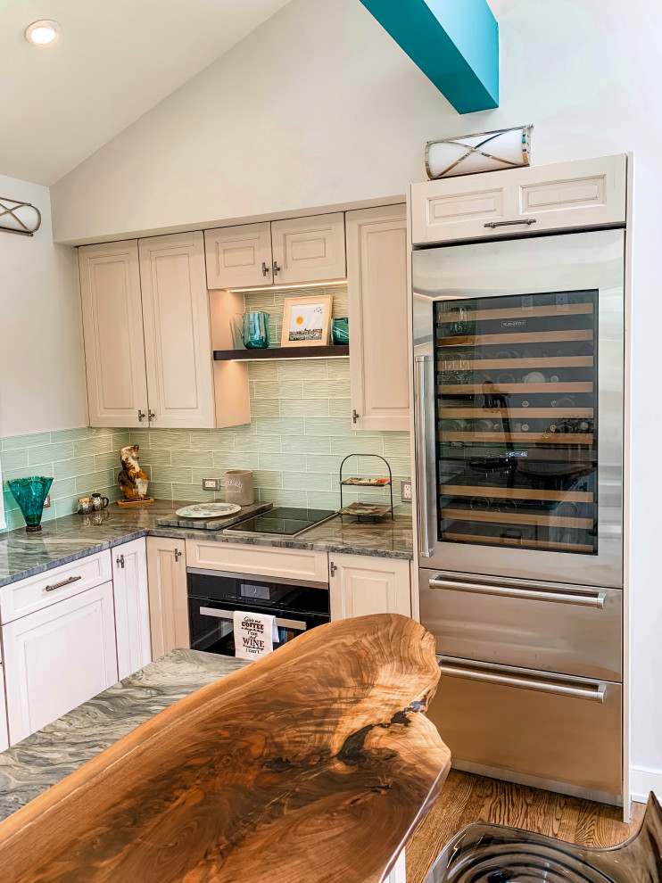 Mid-sized transitional u-shaped open plan kitchen in Baltimore with a farmhouse sink, raised-panel cabinets, white cabinets, granite benchtops, blue splashback, glass tile splashback, stainless steel appliances, medium hardwood floors, no island, brown floor, multi-coloured benchtop and vaulted.