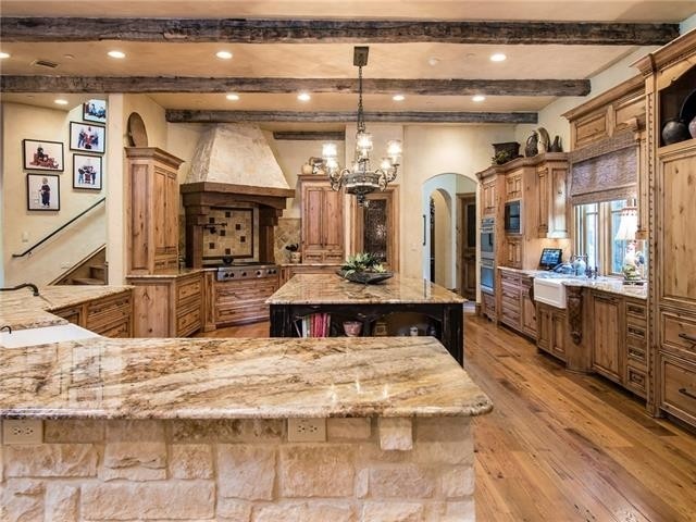Inspiration for a large country open plan kitchen in Austin with a farmhouse sink, raised-panel cabinets, light wood cabinets, granite benchtops, beige splashback, stone tile splashback, panelled appliances, light hardwood floors and with island.