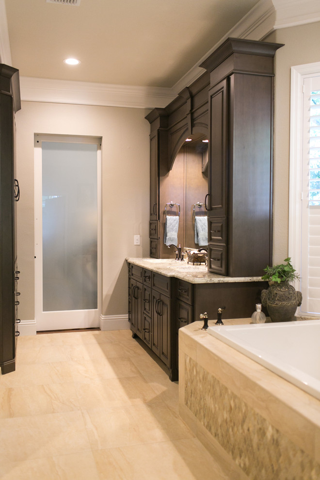 This is an example of a mid-sized traditional master bathroom in Orlando with raised-panel cabinets, dark wood cabinets, a drop-in tub, a curbless shower, beige tile, porcelain tile, beige walls, porcelain floors, an undermount sink and granite benchtops.