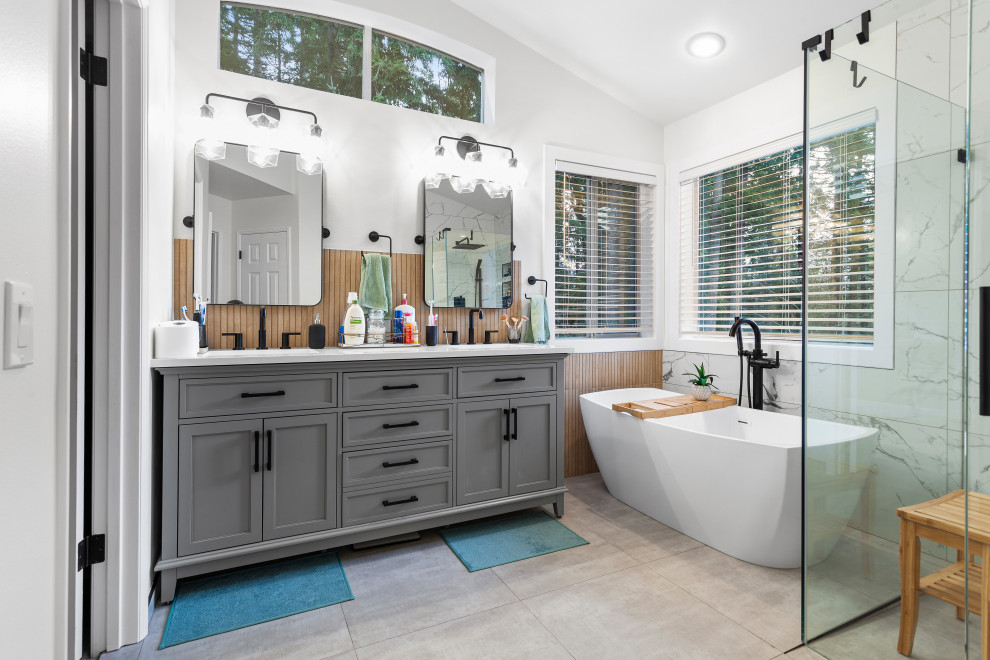 Photo of a mid-sized contemporary master bathroom in Seattle with shaker cabinets, grey cabinets, a freestanding tub, a curbless shower, a bidet, black and white tile, porcelain tile, white walls, porcelain floors, an undermount sink, engineered quartz benchtops, grey floor, a hinged shower door, white benchtops, a niche, a double vanity, a freestanding vanity and wood walls.