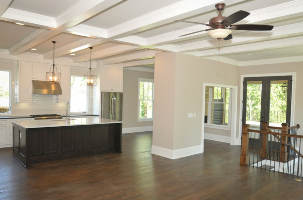 Example of a large transitional l-shaped dark wood floor and brown floor open concept kitchen design in Atlanta with a farmhouse sink, shaker cabinets, white cabinets, quartzite countertops, white backsplash, ceramic backsplash, stainless steel appliances and an island