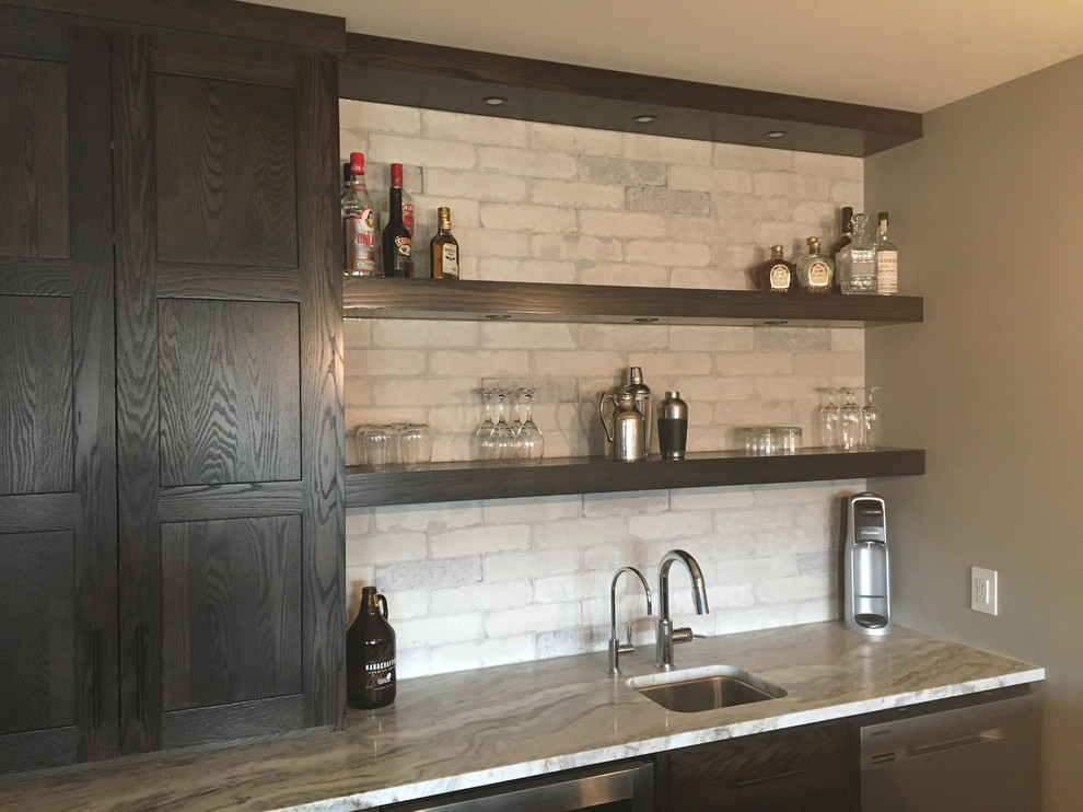 Inspiration for a mid-sized country single-wall wet bar in Other with an undermount sink, shaker cabinets, dark wood cabinets, beige splashback and stone tile splashback.