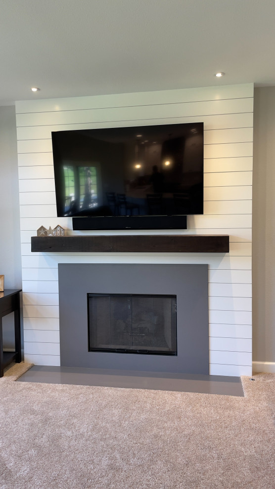 This is an example of a mid-sized transitional open concept family room in Milwaukee with white walls, concrete floors, a standard fireplace, a concrete fireplace surround, a wall-mounted tv, grey floor and planked wall panelling.
