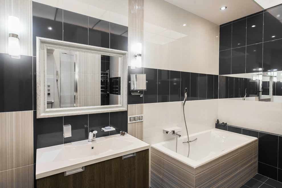 Inspiration for a medium sized contemporary ensuite wet room bathroom in Moscow with flat-panel cabinets, dark wood cabinets, a built-in bath, a wall mounted toilet, black and white tiles, ceramic tiles, white walls, porcelain flooring, a built-in sink, solid surface worktops, black floors and a hinged door.