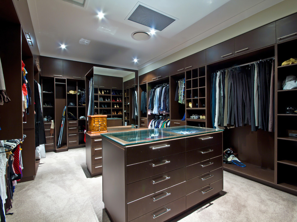 Large gender-neutral walk-in wardrobe in Brisbane with brown cabinets and carpet.
