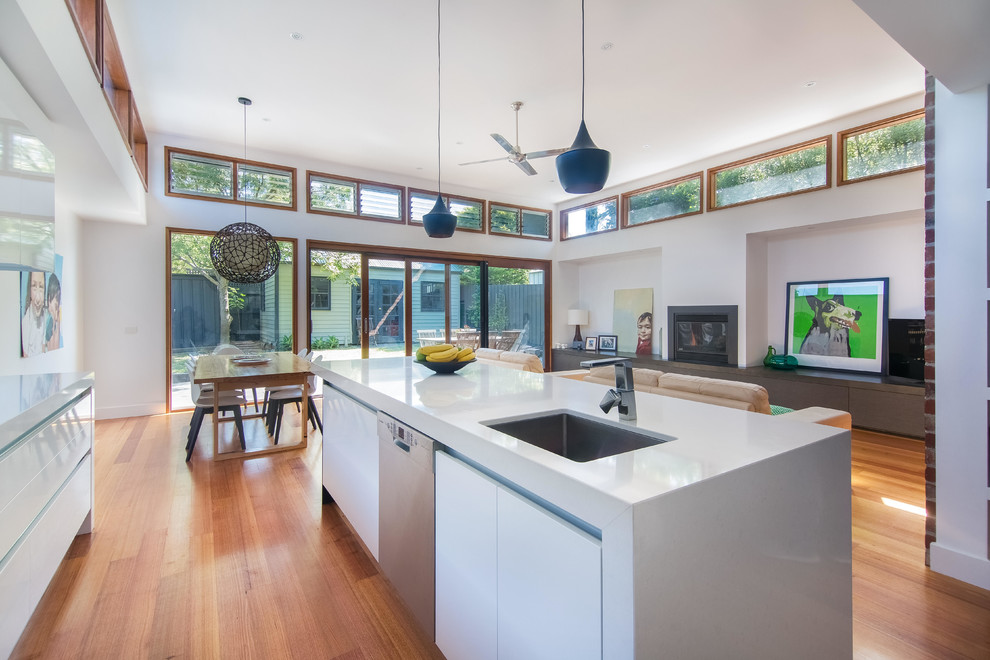 Design ideas for a mid-sized contemporary galley eat-in kitchen in Melbourne with an undermount sink, flat-panel cabinets, white cabinets, quartz benchtops, stainless steel appliances, medium hardwood floors, with island and glass sheet splashback.