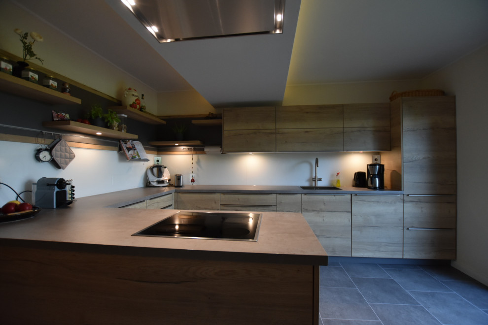 Design ideas for a mid-sized contemporary u-shaped open plan kitchen in Hamburg with a single-bowl sink, flat-panel cabinets, light wood cabinets, concrete benchtops, white splashback, glass sheet splashback, panelled appliances, vinyl floors, a peninsula and grey floor.