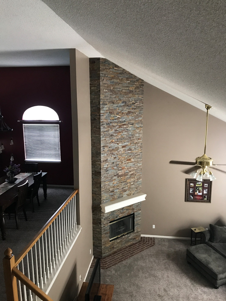 This is an example of a mid-sized contemporary formal open concept living room in Other with grey walls, carpet, a corner fireplace, a stone fireplace surround, no tv and grey floor.