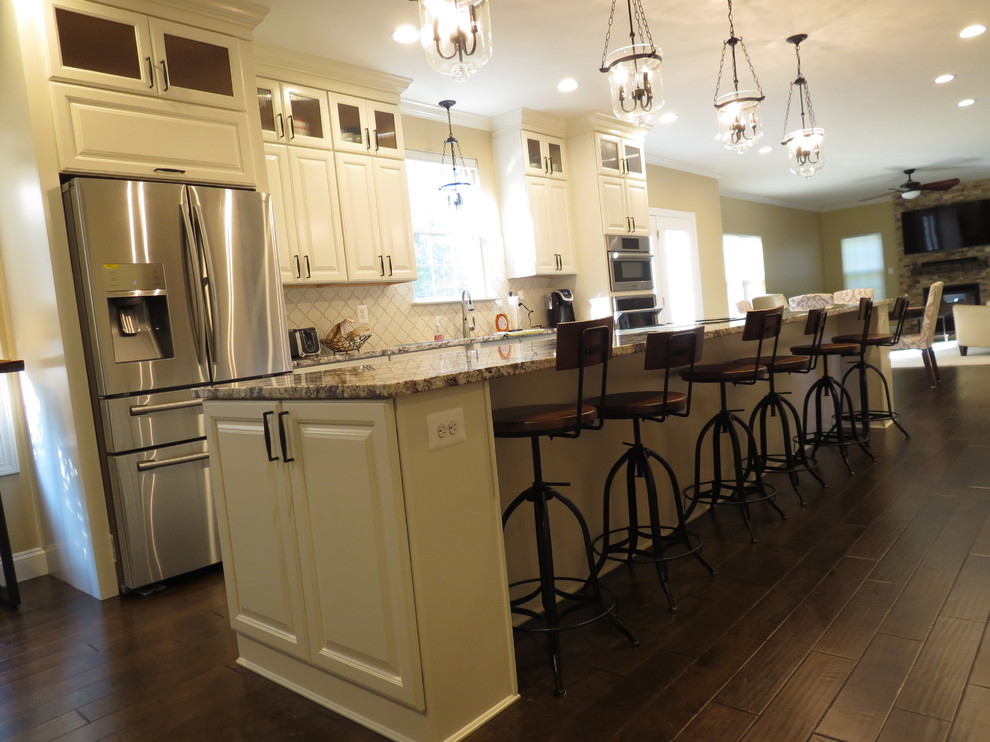 Inspiration for a large transitional galley dark wood floor and brown floor kitchen remodel with a double-bowl sink, raised-panel cabinets, white cabinets, granite countertops, white backsplash, porcelain backsplash, stainless steel appliances and an island