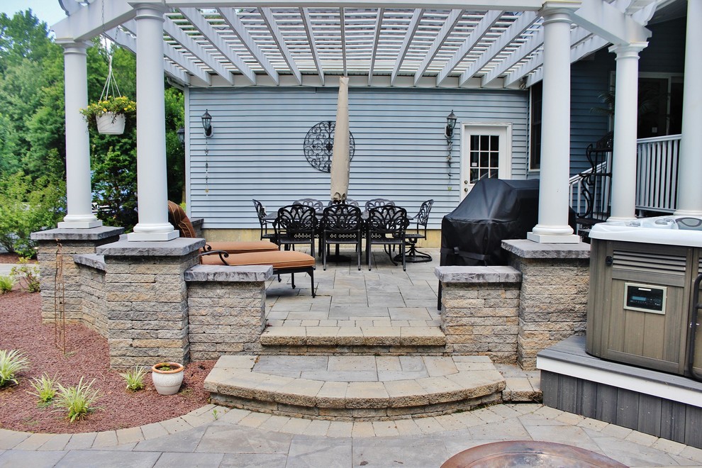 Design ideas for a large traditional backyard patio in Philadelphia with a water feature, natural stone pavers and a roof extension.