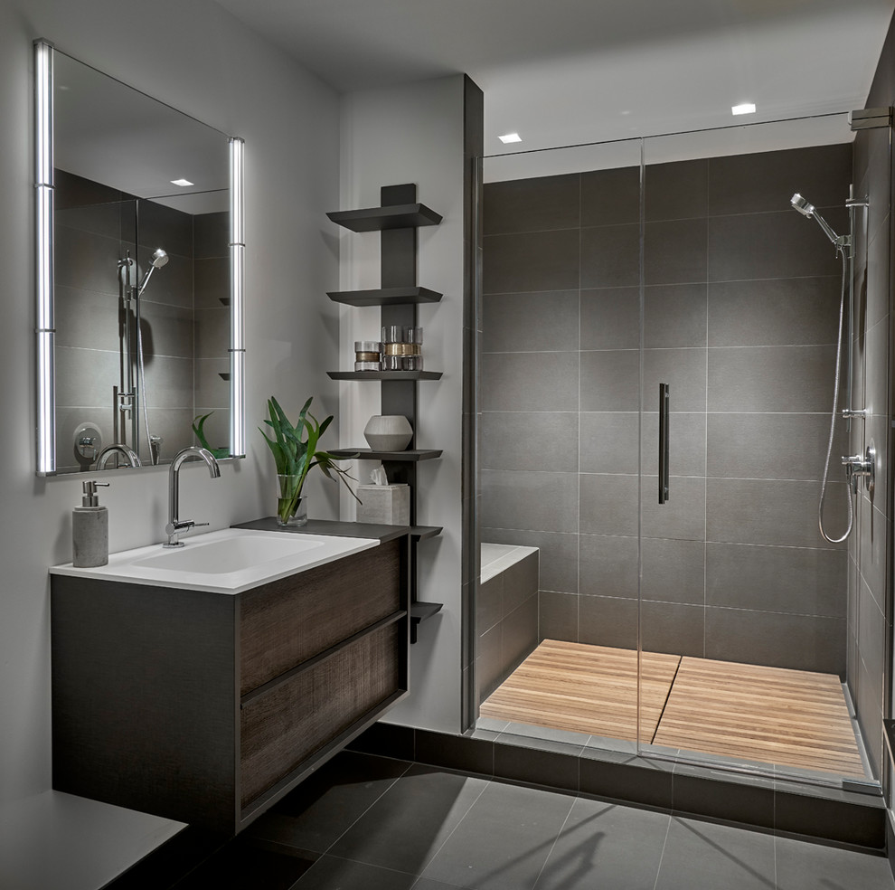 Inspiration for a contemporary bathroom in Chicago with flat-panel cabinets, dark wood cabinets, an alcove shower, gray tile, grey walls, an integrated sink, grey floor and a hinged shower door.