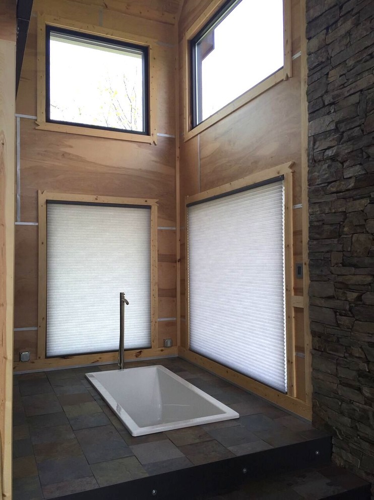 Inspiration for a mid-sized rustic slate floor drop-in bathtub remodel in Indianapolis with flat-panel cabinets, black cabinets, an integrated sink and quartz countertops