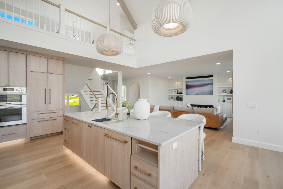 Inspiration for a large transitional l-shaped light wood floor, beige floor and vaulted ceiling eat-in kitchen remodel with an undermount sink, recessed-panel cabinets, light wood cabinets, quartzite countertops, white backsplash, granite backsplash, stainless steel appliances, an island and white countertops