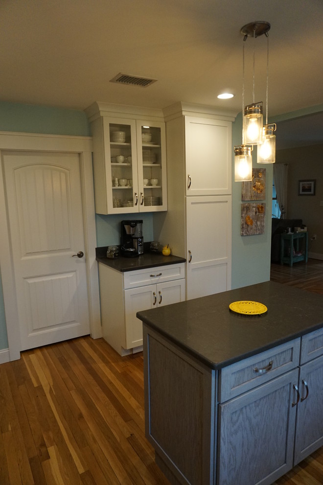 Example of a mid-sized transitional u-shaped medium tone wood floor eat-in kitchen design in Boston with an undermount sink, shaker cabinets, gray cabinets, quartz countertops, black backsplash, stainless steel appliances and an island