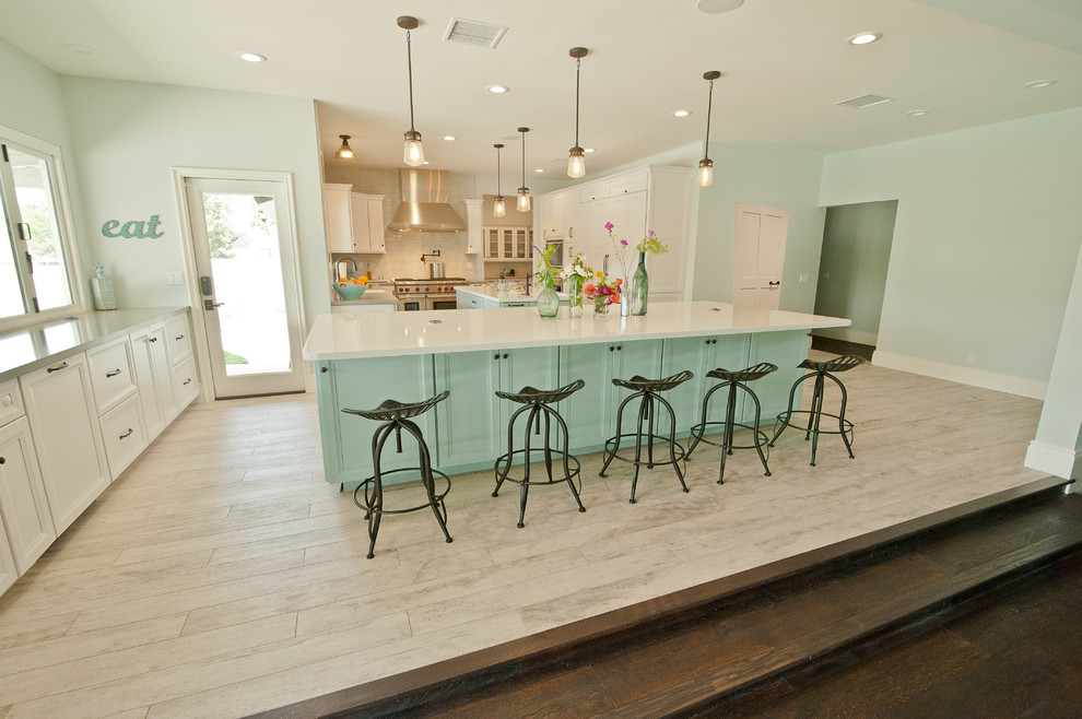 Design ideas for an expansive beach style u-shaped open plan kitchen in Orange County with a farmhouse sink, raised-panel cabinets, white cabinets, quartz benchtops, blue splashback, ceramic splashback, stainless steel appliances, ceramic floors and multiple islands.