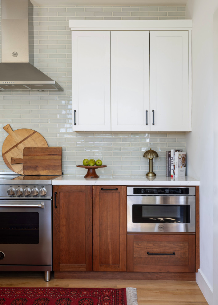 Mid-sized arts and crafts l-shaped light wood floor and beige floor enclosed kitchen photo with a farmhouse sink, recessed-panel cabinets, wood countertops, green backsplash, ceramic backsplash, stainless steel appliances, an island and brown countertops