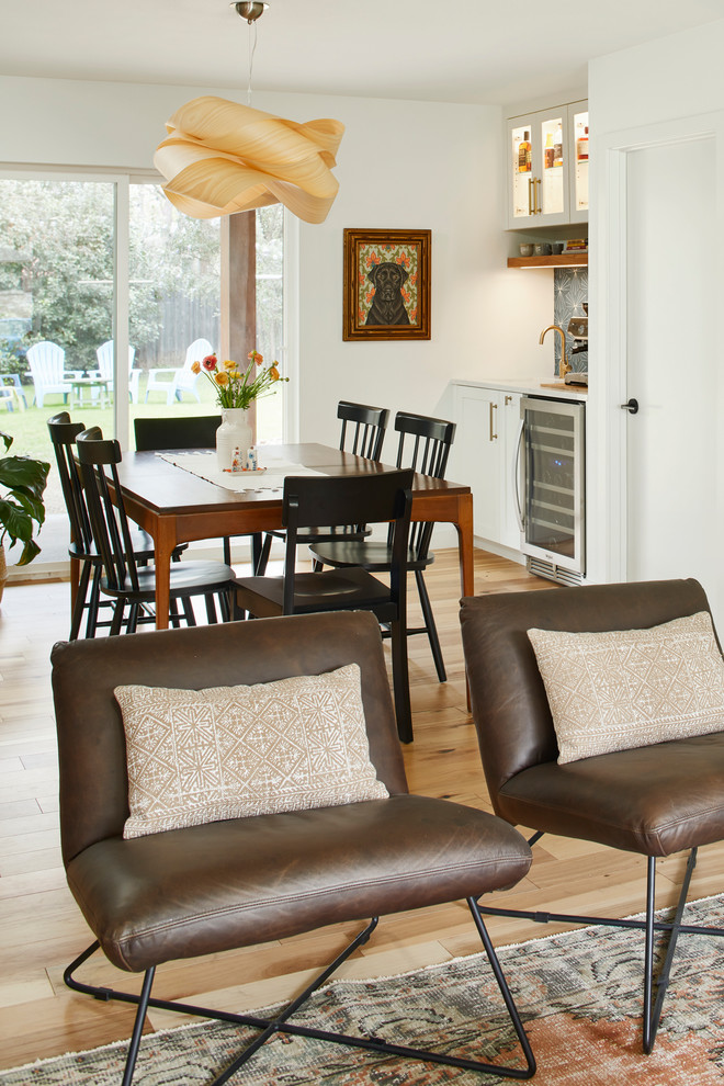 Photo of a mid-sized midcentury dining room in Austin with white walls, light hardwood floors, no fireplace and brown floor.