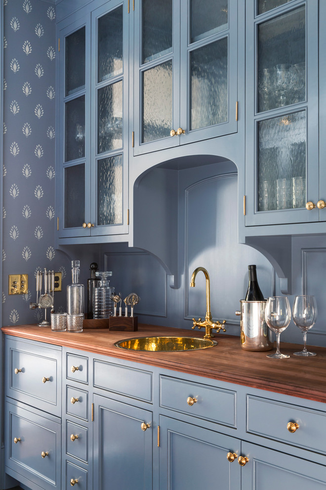 Photo of a large classic galley wet bar in San Francisco with a built-in sink, blue cabinets, wood worktops, brown worktops, glass-front cabinets, blue splashback, wood splashback, dark hardwood flooring and brown floors.